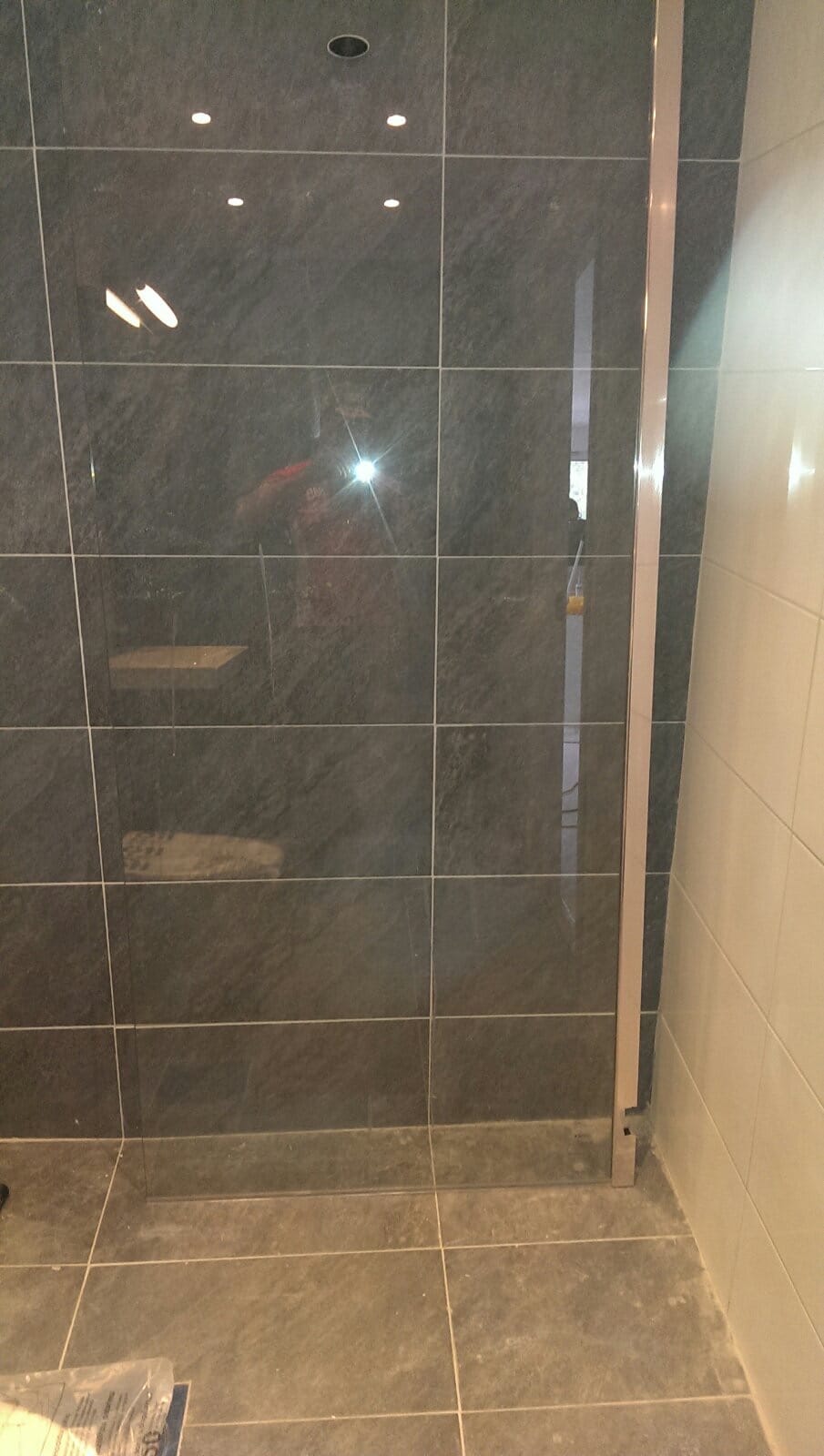 Duschvägg i glas med grå klinker och vita väggplattor