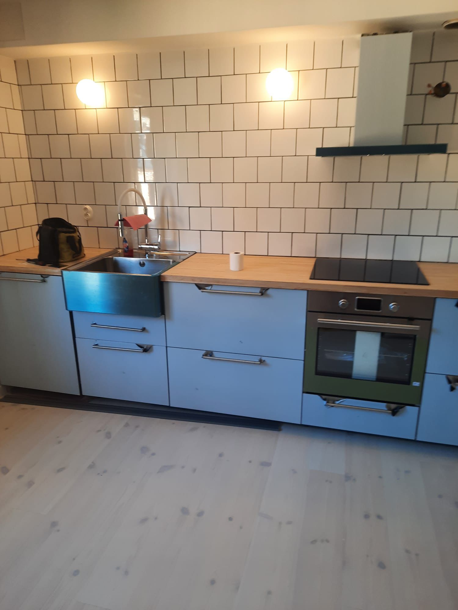 Kök med blå luckor, vitt kakel och träbänkskiva