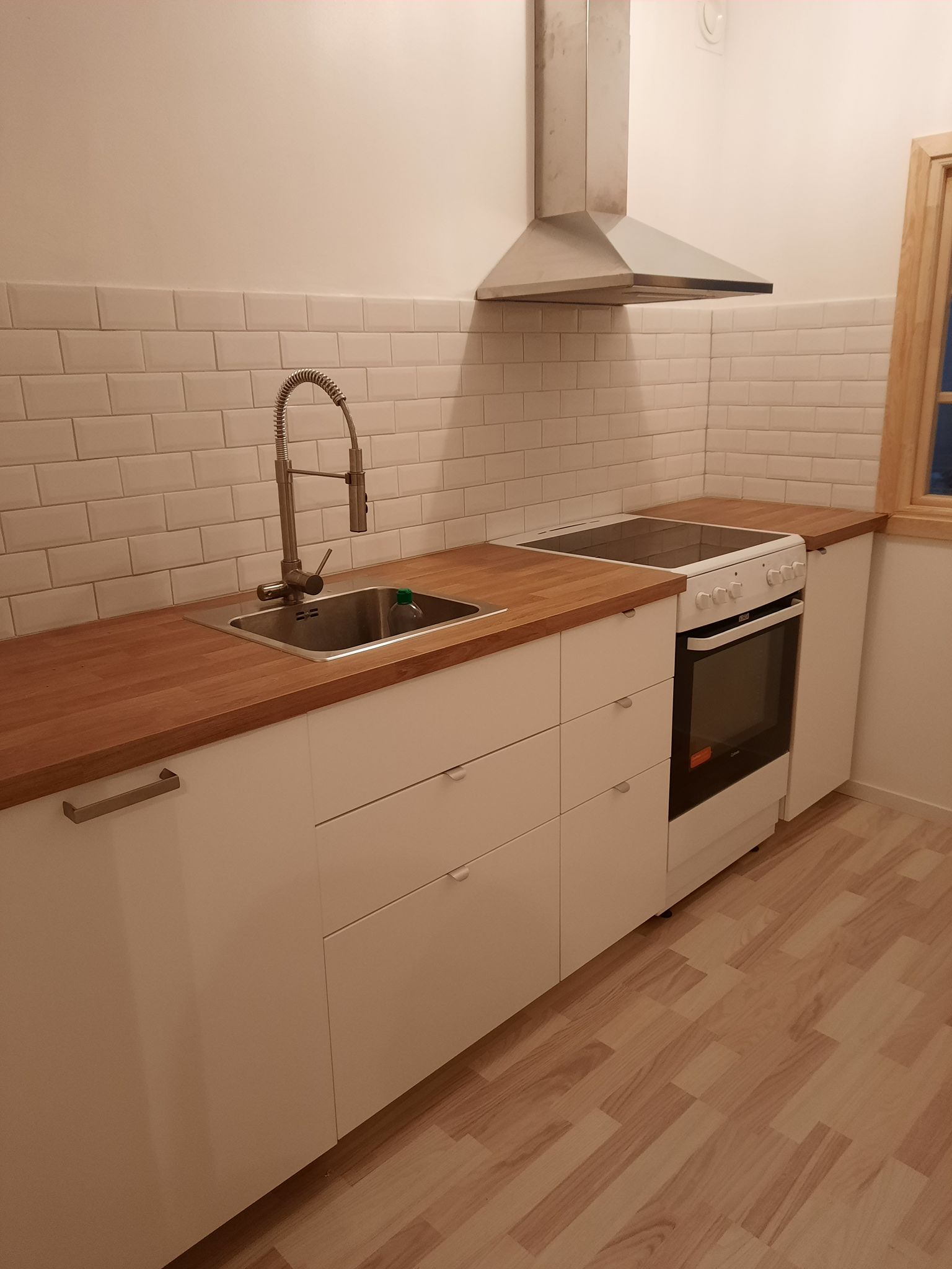 Ljust kök med träbänkskiva och vitt kakel