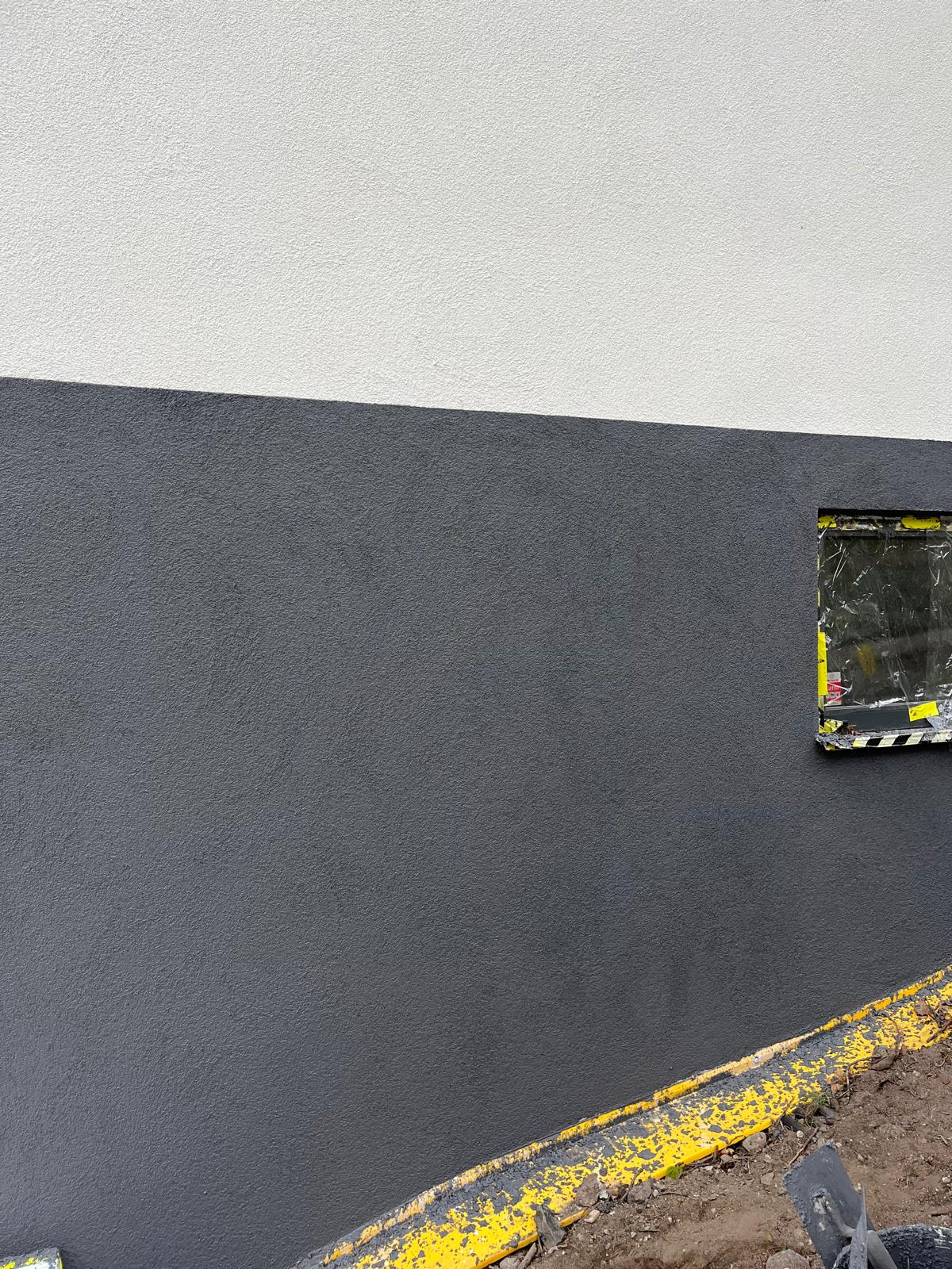 Detalj av rak linje mellan vit fasad och mörkgrå sockel